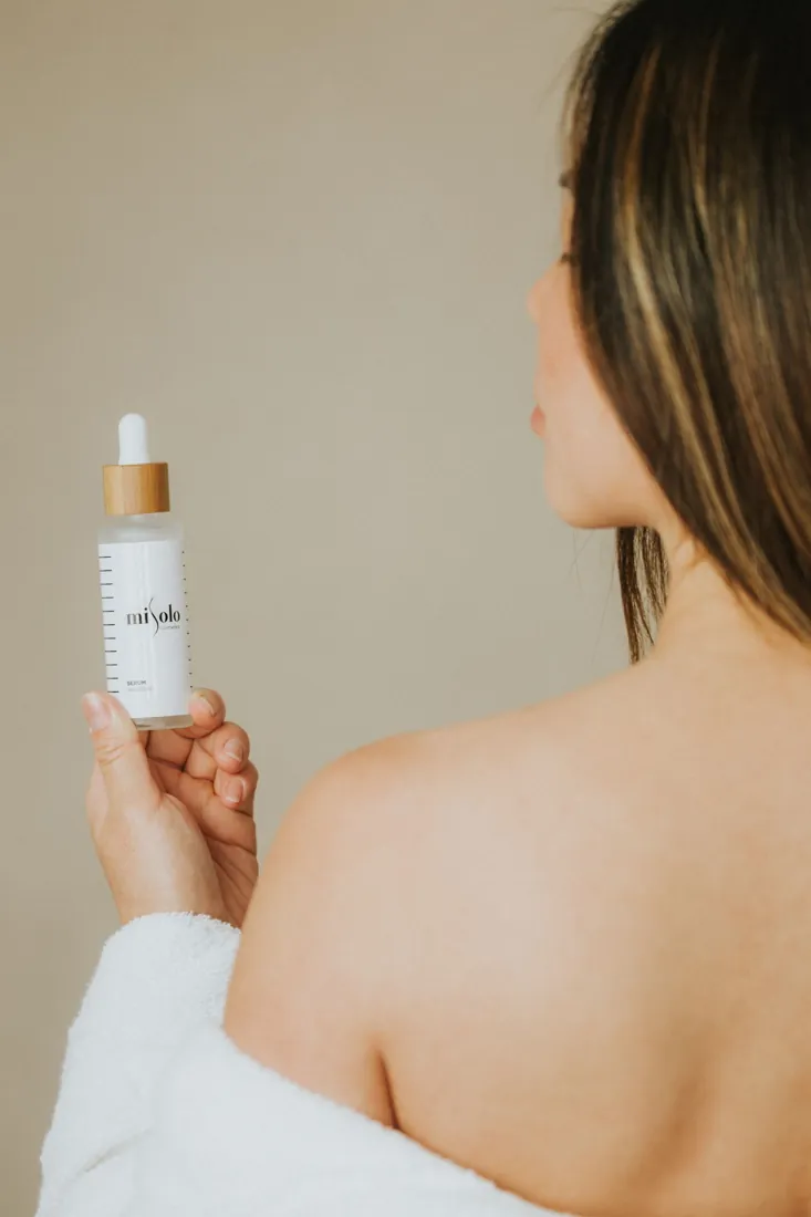 Woman holding a skincare serum as part of a red light skincare ritual